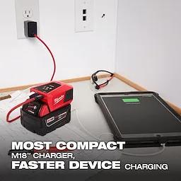 The M18™ TOP-OFF™ Charger & Power Supply is plugged into a wall socket, charging a tablet on a desk with blueprints. The product is labeled as the most compact M18™ charger, providing faster device charging, clearly highlighted by the text in the image.