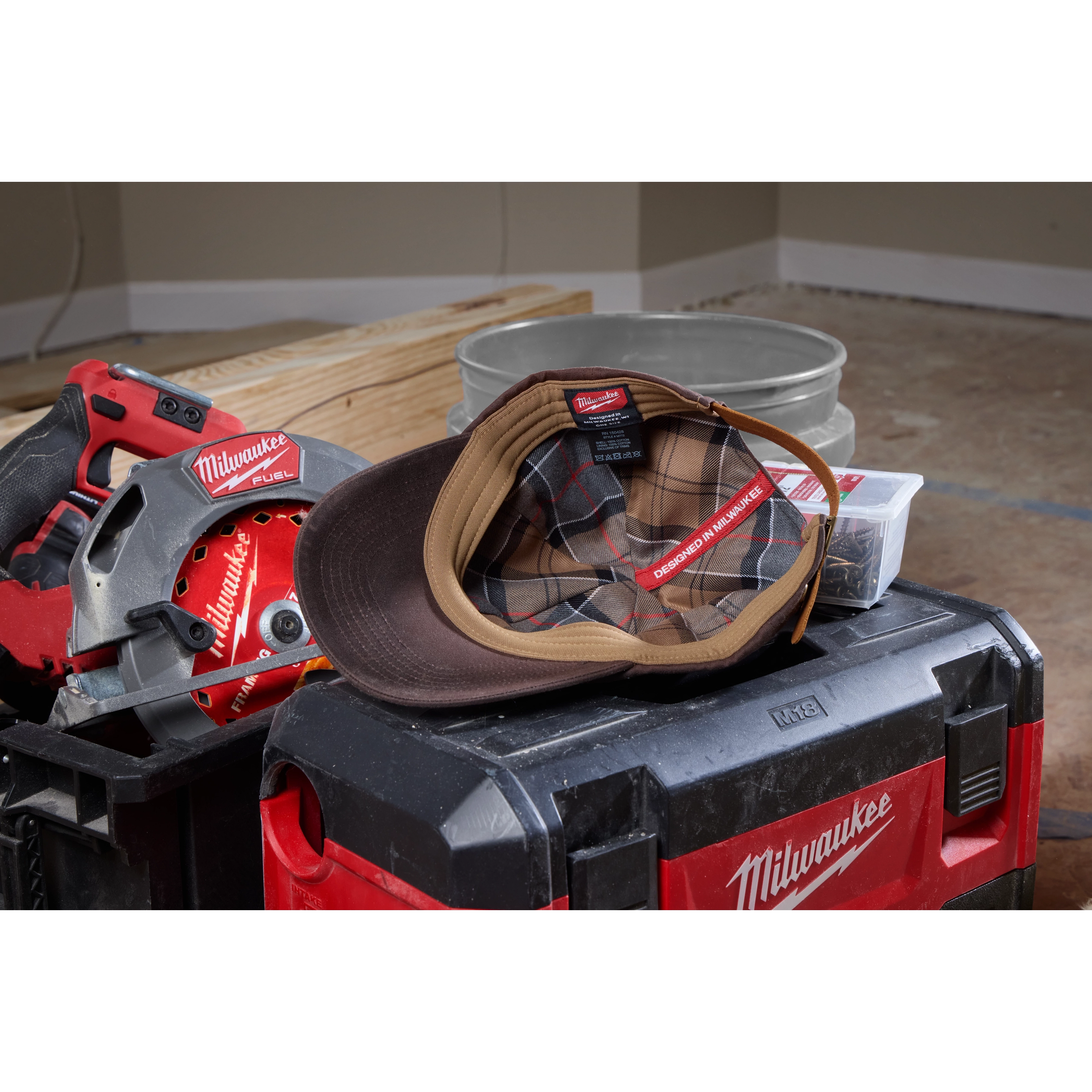 Waxed Canvas Adjustable Hat displayed on a red and black tool case in a workshop setting with power tools in the background.
