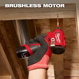 A gloved hand holds a Milwaukee brushless motor drill, screwing a fastener into a wooden beam within a construction area.
