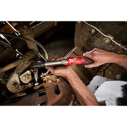 Hands using an M12 FUEL 1/2" Extended Reach Ratchet to tighten a bolt in a metal machinery area.