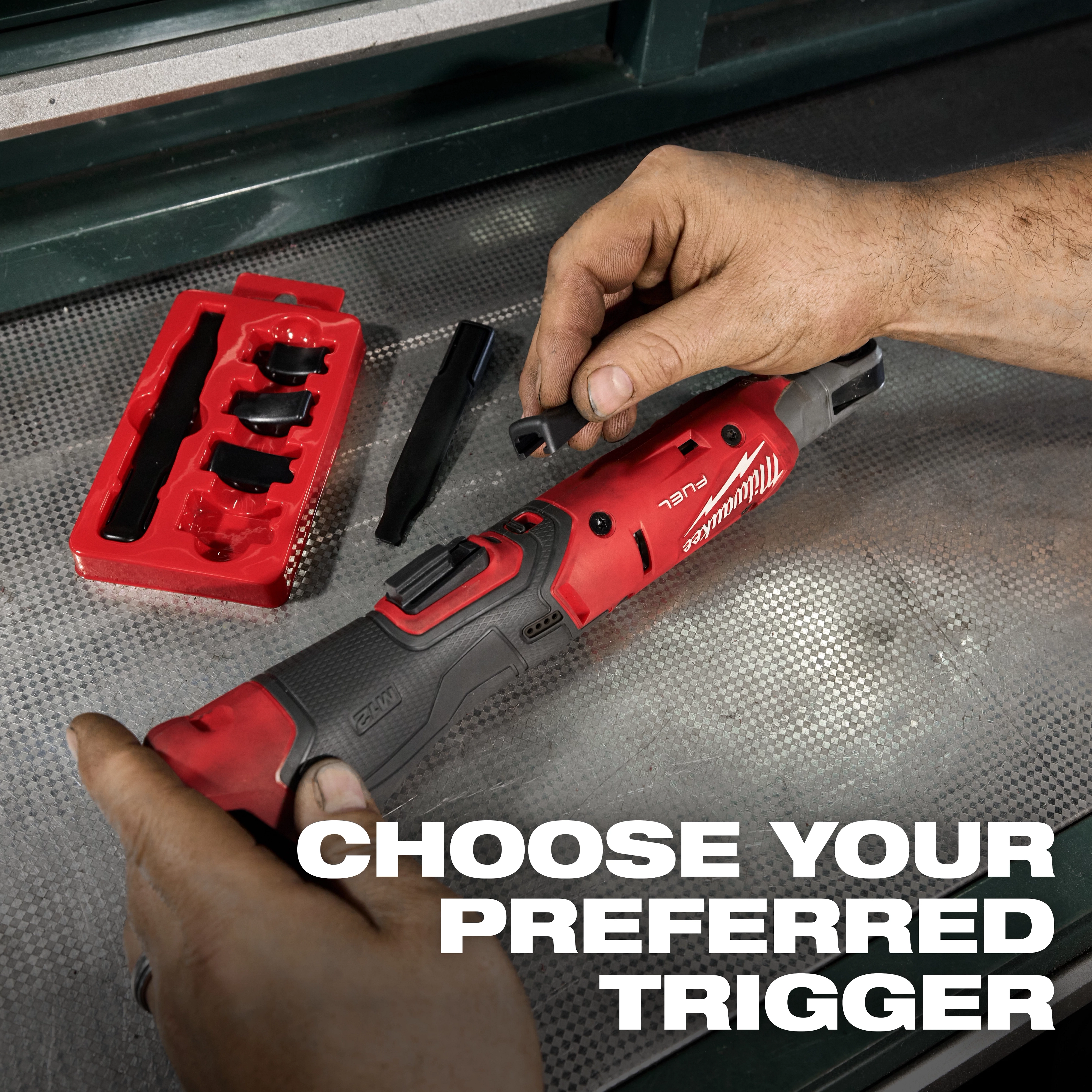 The M12 FUEL™ Ratchet Modular Trigger Cap Kit allows customization of the ratchet trigger with various detachable caps. A hand is seen changing the trigger cap on the ratchet, while several trigger caps are shown in a red tray. Text reads, "Choose your preferred trigger."