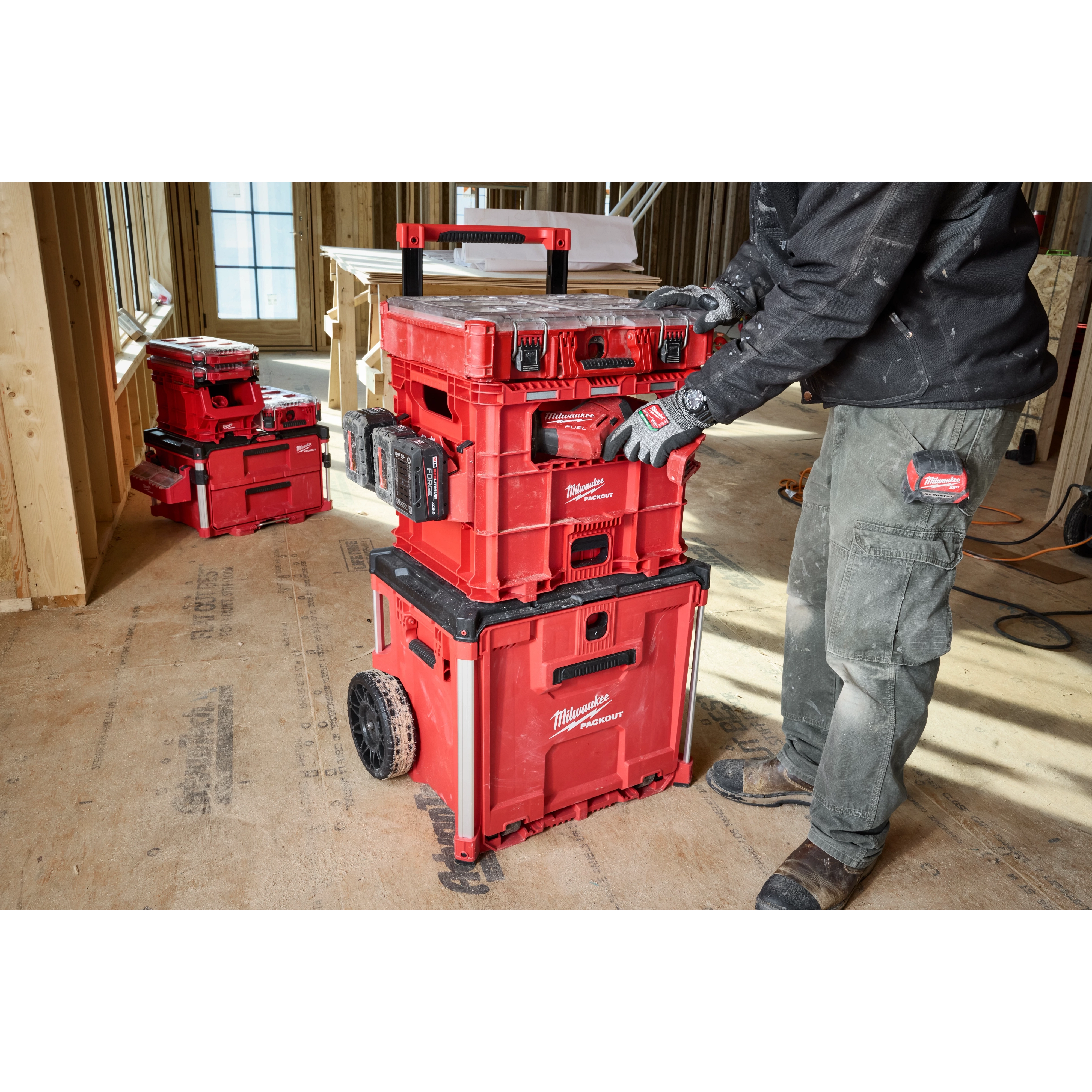 Person using Milwaukee PACKOUT XL Crate in a woodwork environment. Several red storage crates are stacked and organized on a wheeled cart.