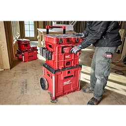 Person using Milwaukee PACKOUT XL Crate in a woodwork environment. Several red storage crates are stacked and organized on a wheeled cart.