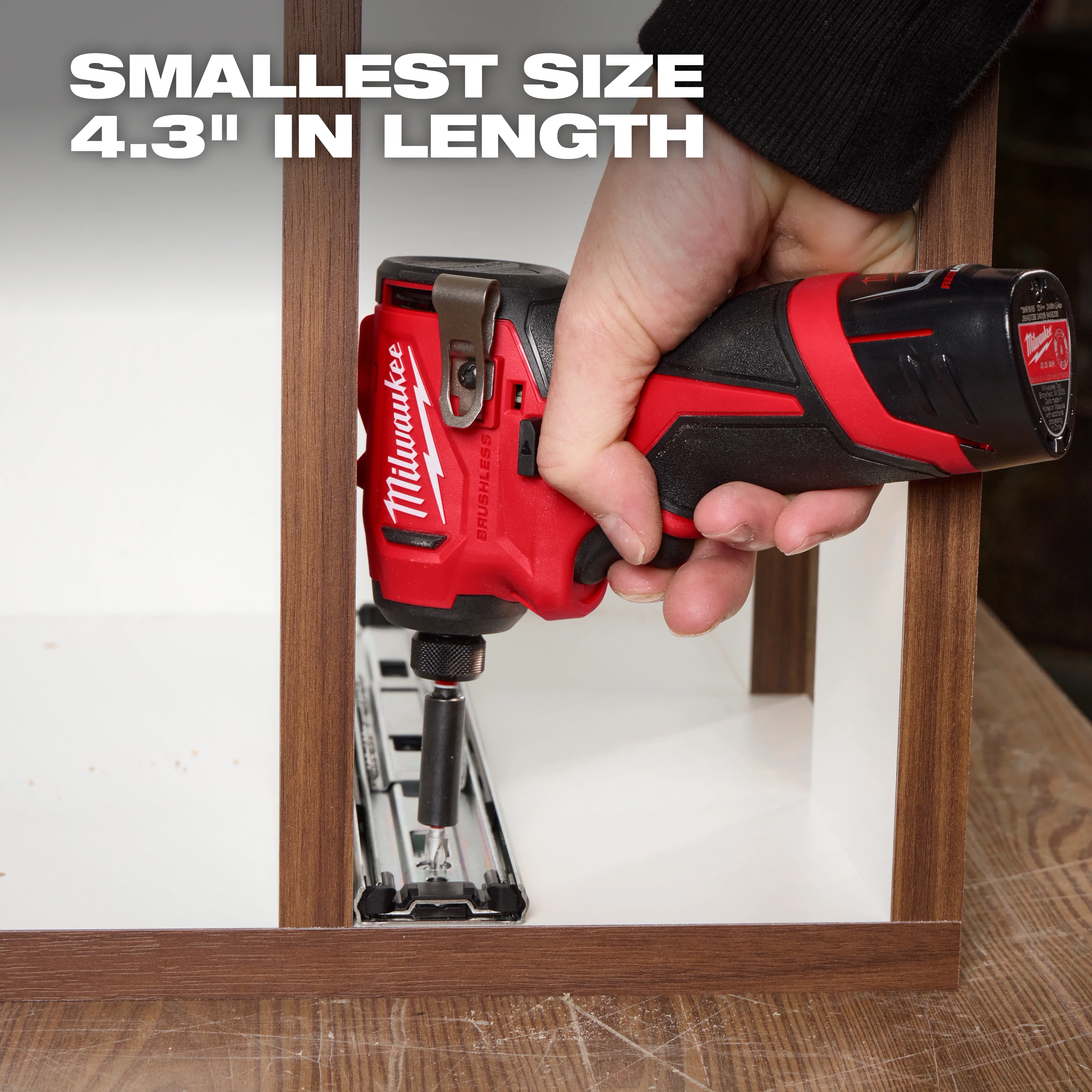 A hand uses a red and black Milwaukee cordless power tool to screw a metal piece onto a wooden frame. The text "SMALLEST SIZE 4.3'' IN LENGTH" is displayed in the upper left corner of the image.