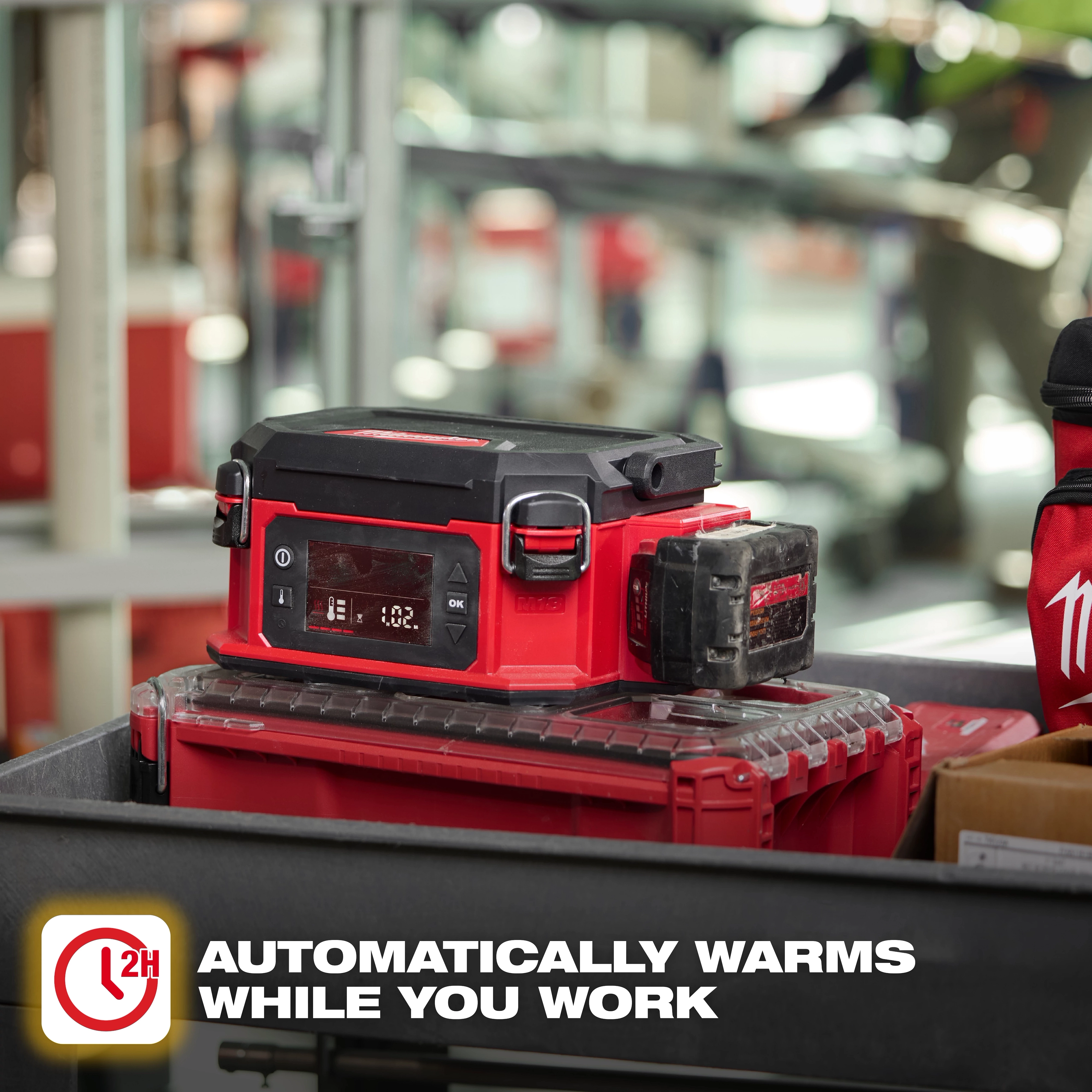 Red M18 Jobsite Lunch Warmer on a work cart with tools in an industrial workspace.