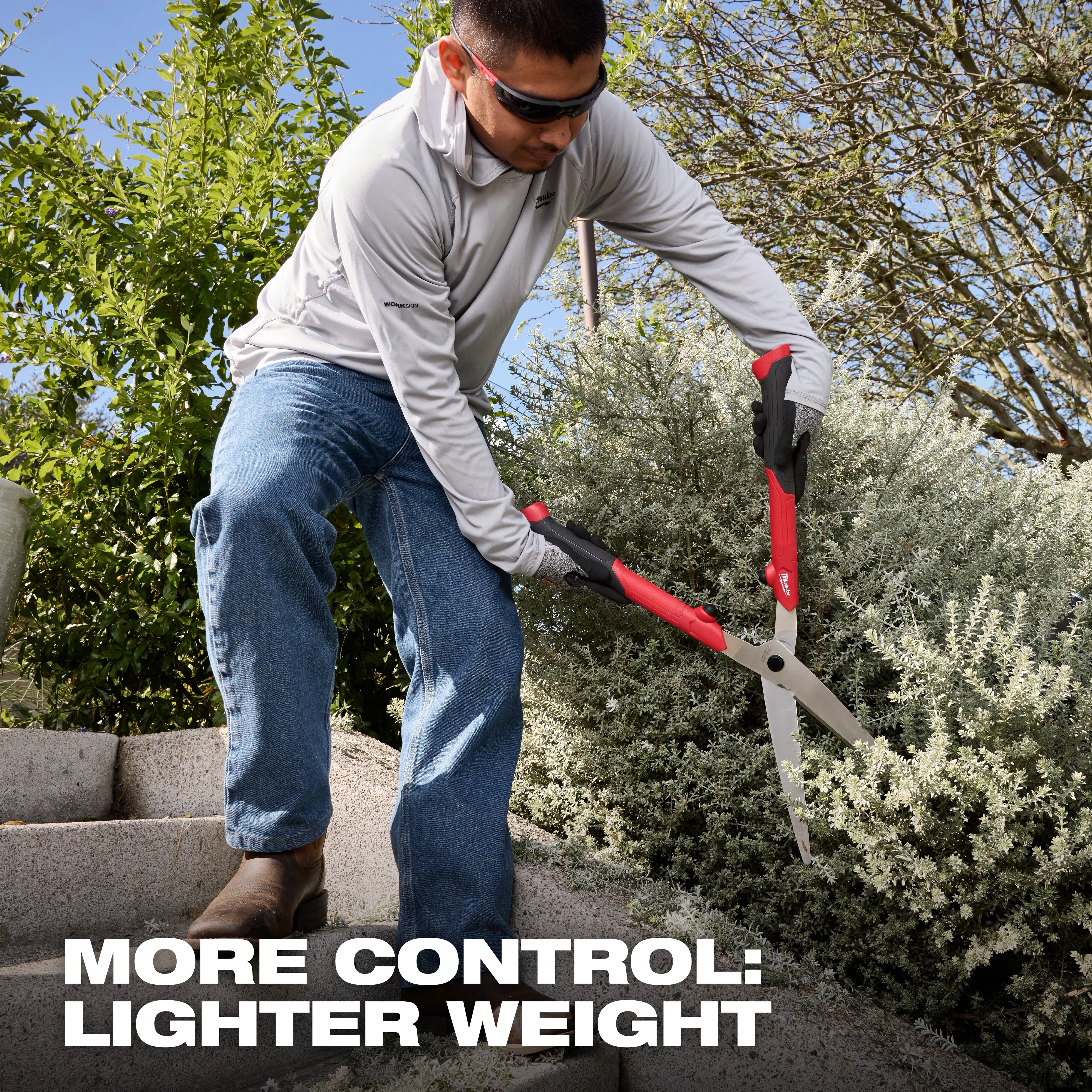 Person trimming a shrub on outdoor steps using 10” Hedge Shears with red and black handles.