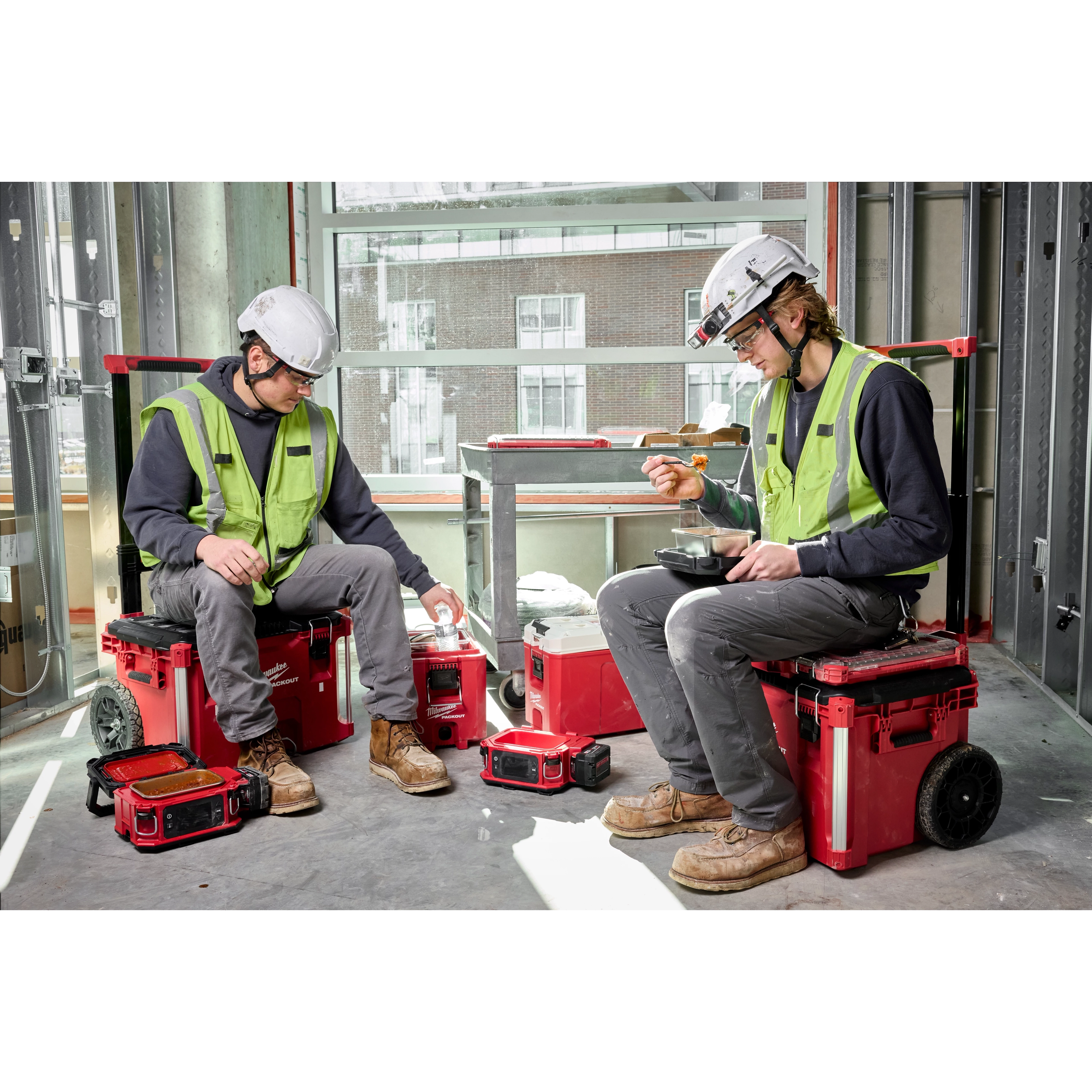Two construction workers enjoy lunch on-site, using the M18 Jobsite Lunch Warmer.
