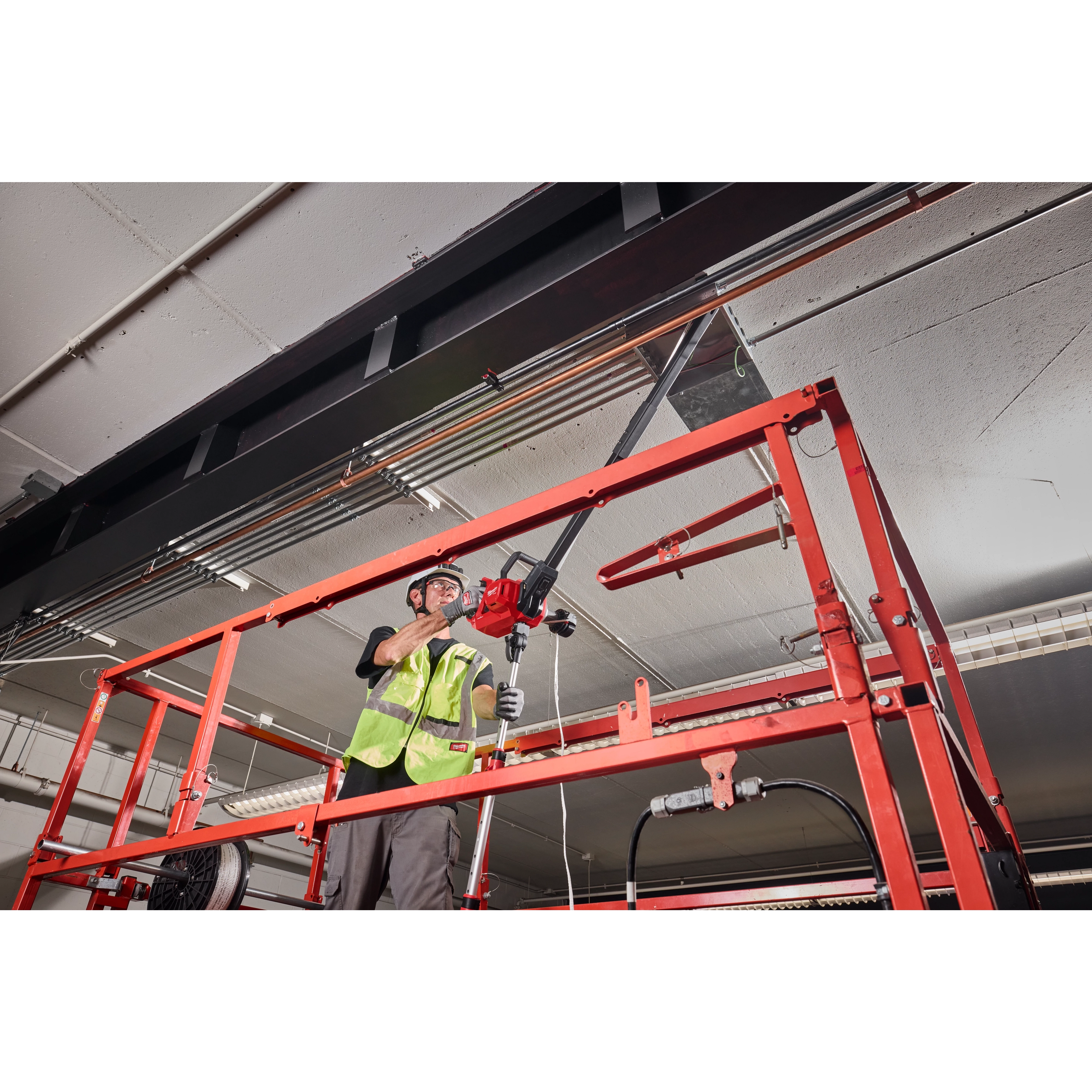 Worker on an elevated platform using an M18 FUEL 1K Wire Puller to pull cable overhead.