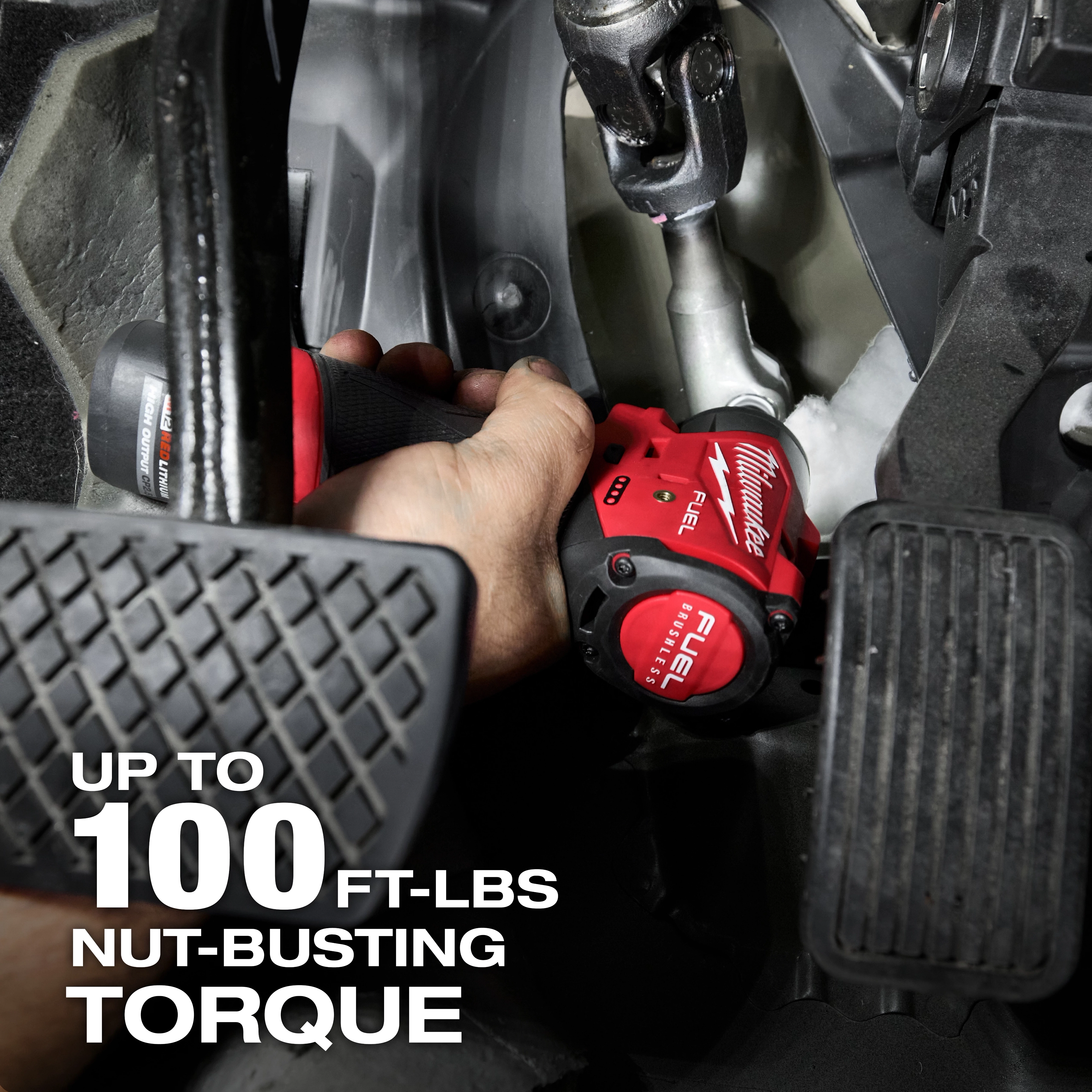 A hand using the M12 FUEL™ 1/4" Subcompact Impact Wrench w/ Friction Ring to work on a vehicle. The image highlights that the tool delivers up to 100 ft-lbs of nut-busting torque.