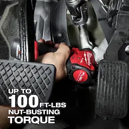 A hand using the M12 FUEL™ 1/4" Subcompact Impact Wrench w/ Friction Ring to work on a vehicle. The image highlights that the tool delivers up to 100 ft-lbs of nut-busting torque.
