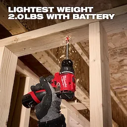 A person wearing gloves uses a red Milwaukee drill to bore a hole through a wooden beam in a construction setting. Sawdust is visible around the drilling spot. The text above reads "LIGHTEST WEIGHT 2.0 LBS WITH BATTERY."